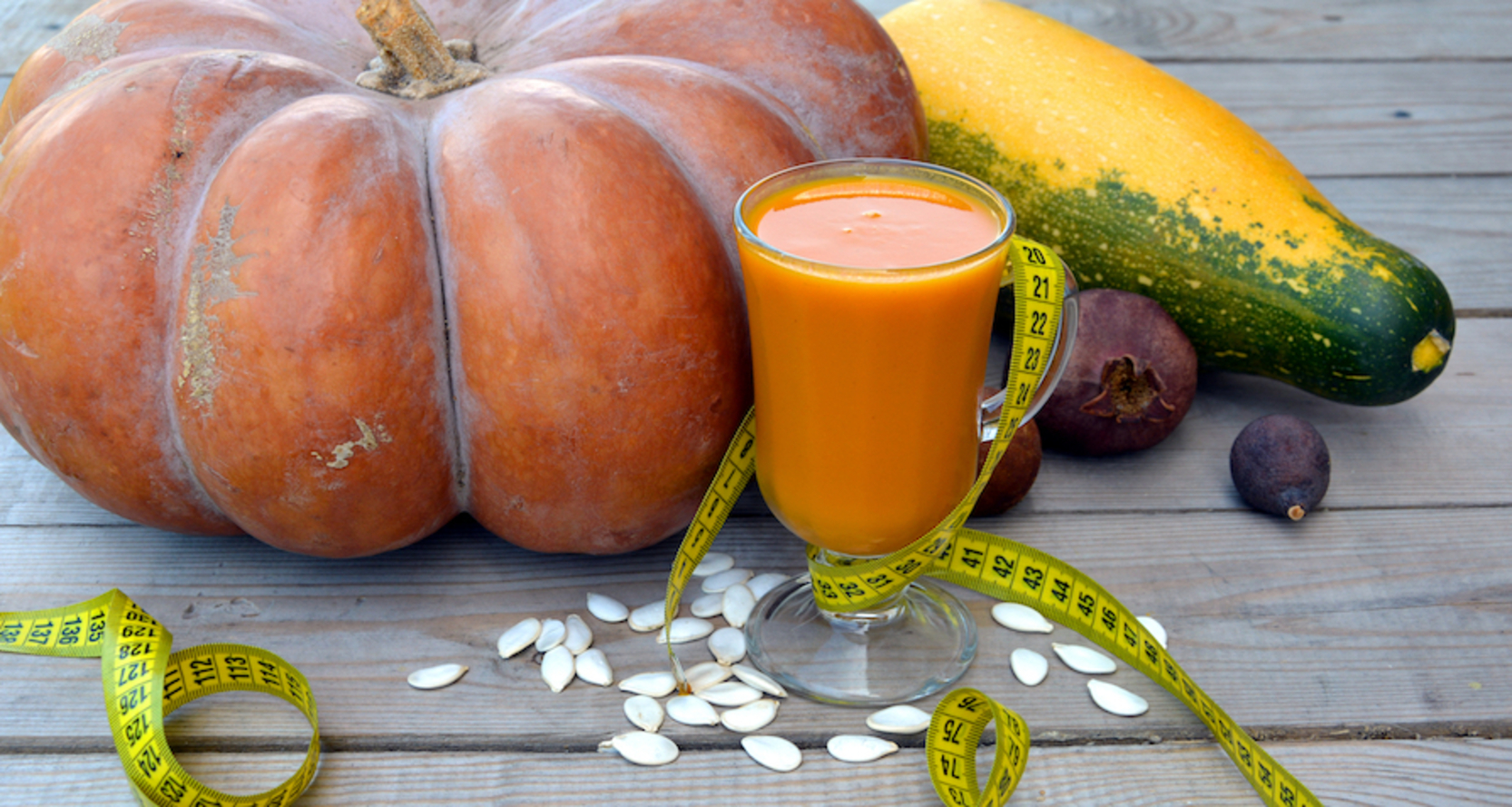 A selection of gourds, seeds, and autumn fruit with a yellow tape measure wound them