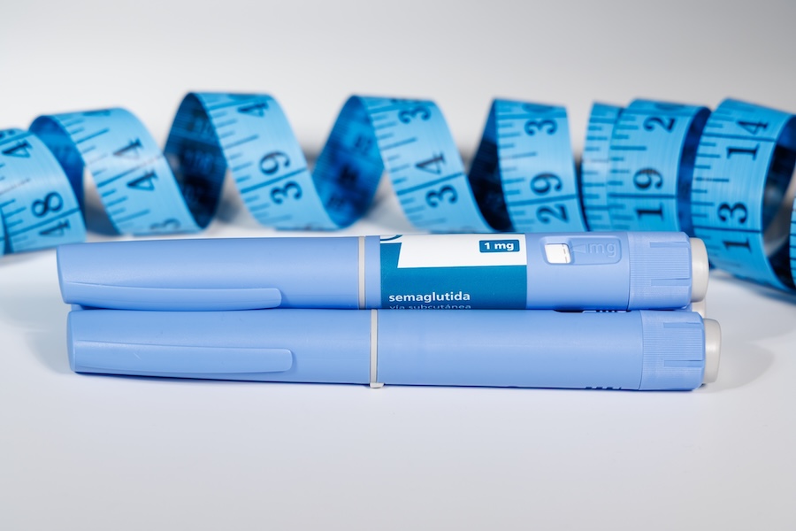 Two blue weight loss injection pens and a blue tape measure