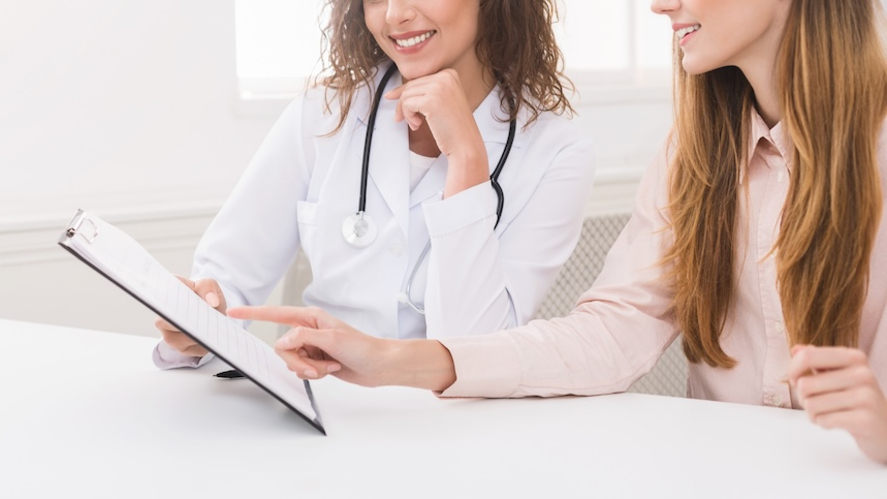 Friendly doctor discussing health plan with a patient on a clipboard during a weight loss appointment in Houma, LA.